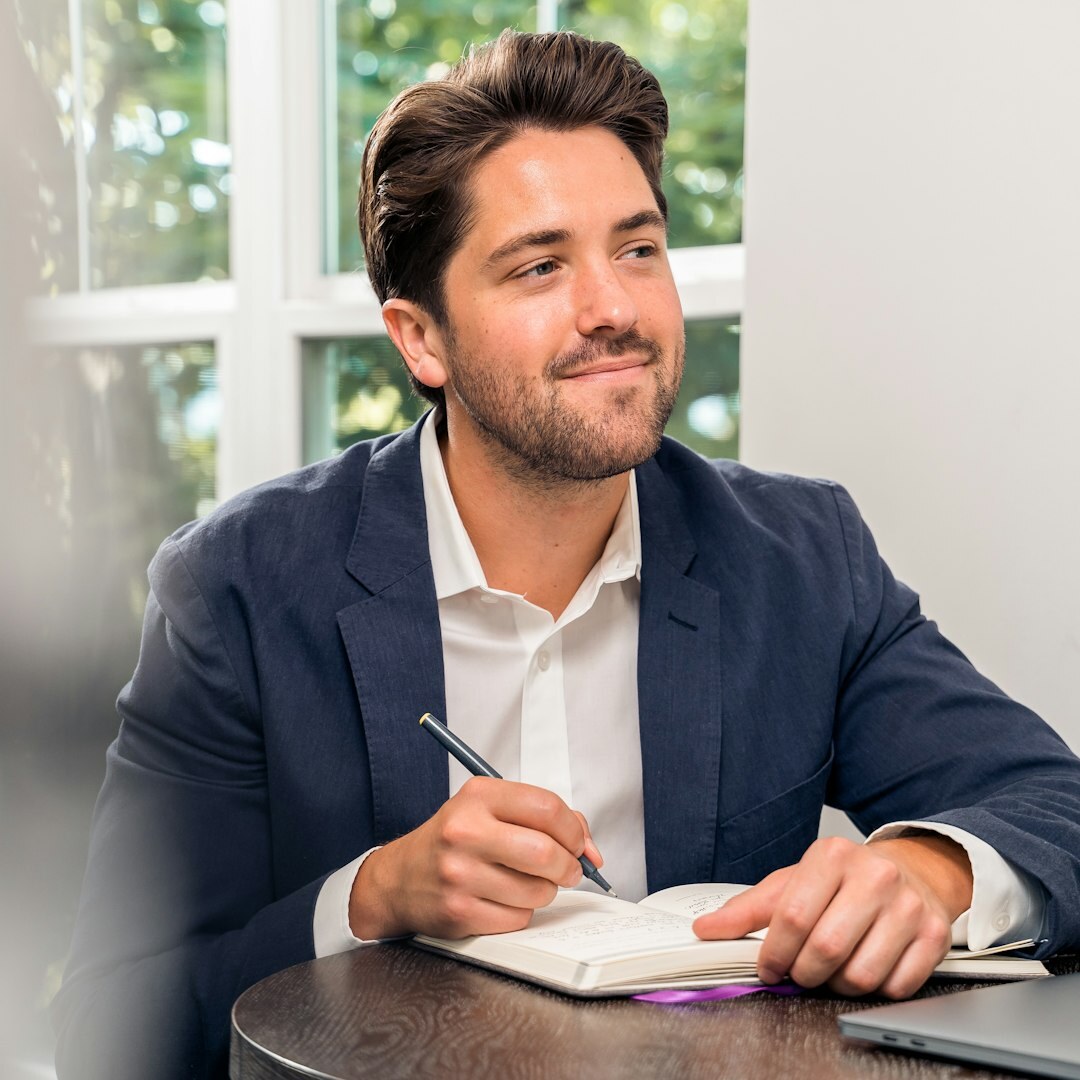 Young man typing on a laptop while taking notes for a course